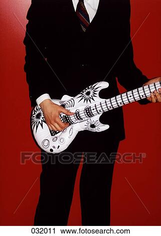 Stock Image - A businessman playing a plastic guitar. Fotosearch