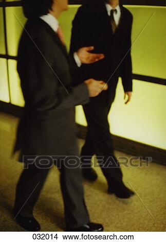Picture - Two businessmen having a discussion while walking. Fotosearch