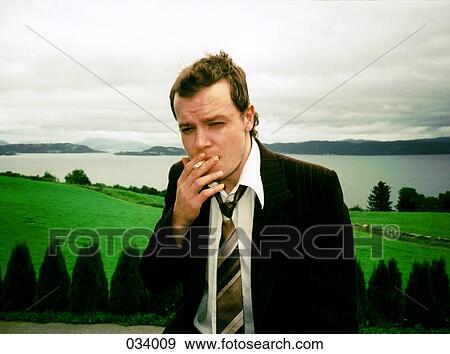 Man smoking a cigarette in front of countryside landscape View Large Photo Image Stock Photo - Man smoking a cigarette in front of countryside landscape. Fotosearch