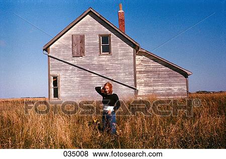 A woman standing in a field in front of a house View Large Photo Image Stock Photo - A woman standing in a field in front of a house. Fotosearch