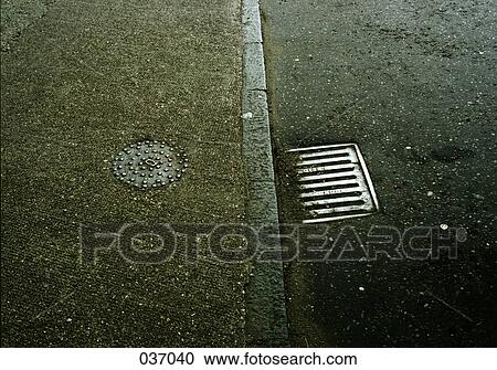 Stock Image - A gutter on the road alongside a sidewalk. Fotosearch