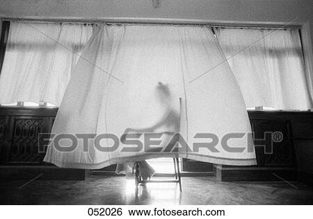 A woman sitting in a chair, covered by a curtain View Large Photo Image Stock Photograph - A woman sitting in a chair, covered by a curtain. Fotosearch