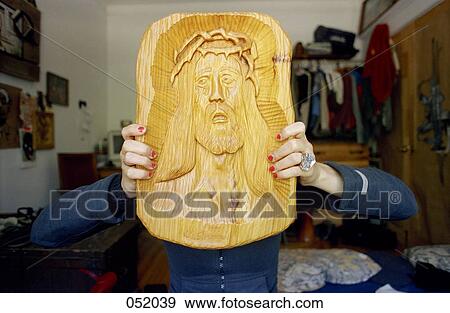 A young woman holding a carving of Jesus in front of her face View Large Photo Image Stock Photo - A young woman holding a carving of Jesus in front of her face. Fotosearch