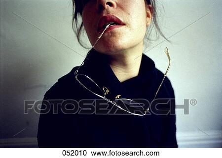 A young woman holds a pair of sunglasses between her teeth View Large Photo Image Stock Image - A young woman holds a pair of sunglasses between her teeth . Fotosearch