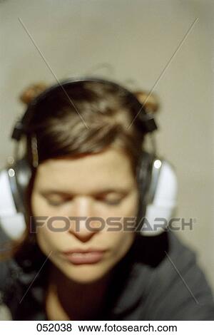 A young woman listening to headphones View Large Photo Image Stock Photo - A young woman listening to headphones. Fotosearch