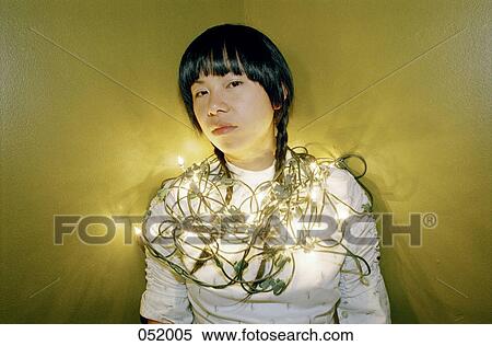 A young woman looking forward, wrapped in Christmas lights View Large Photo Image Stock Photography - A young woman looking forward, wrapped in Christmas lights. Fotosearch