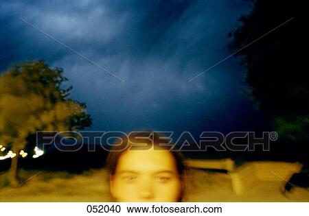 Stock Image - A young woman standing under stormclouds. Fotosearch