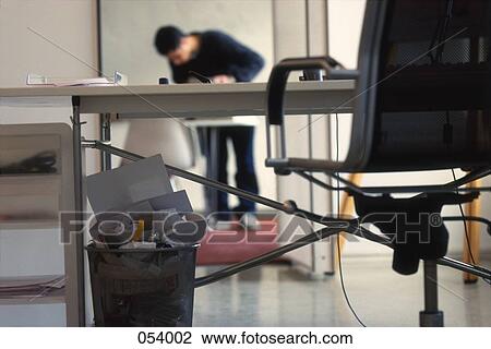 A man working in the background of an office View Large Photo Image Stock Image - A man working in the background of an office. Fotosearch