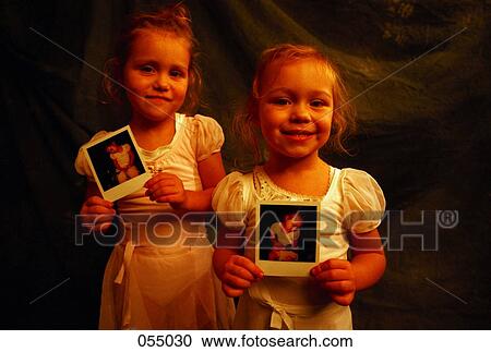 Two girls holding pictures of themselves View Large Photo Image Stock Image - Two girls holding pictures of themselves. Fotosearch