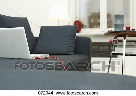 A laptop on a couch in a living room View Large Photo Image Picture - A laptop on a couch in a living room. Fotosearch