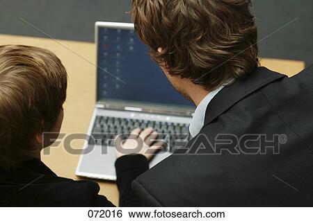 Stock Photograph - A man and a woman looking at a laptop. Fotosearch