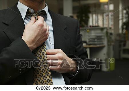 A man in a suit tugging straightening his necktie View Large Photo Image Stock Image - A man in a suit tugging straightening his necktie. Fotosearch