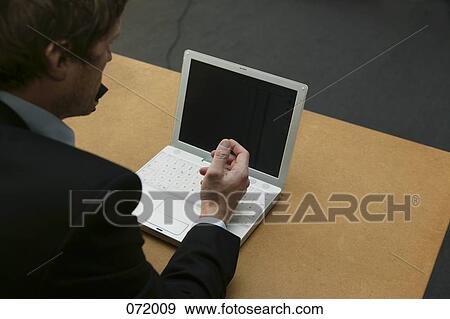 A man sitting at a desk talking on the telephone View Large Photo Image Stock Photo - A man sitting at a desk talking on the telephone. Fotosearch