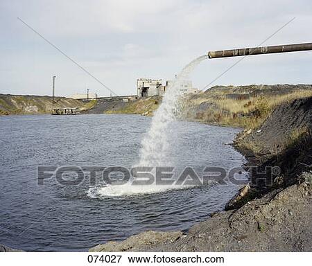 Stock Photo - An industrial drainpipe shooting water into a lake. Fotosearch