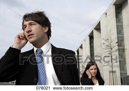 A businessman and a businesswoman talking on cell phones View Large Photo Image Stock Image - A businessman and a businesswoman talking on cell phones. Fotosearch