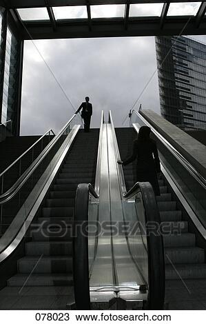A businessman and a businesswoman riding an escalator View Large Photo Image Stock Image - A businessman and a businesswoman riding an escalator. Fotosearch