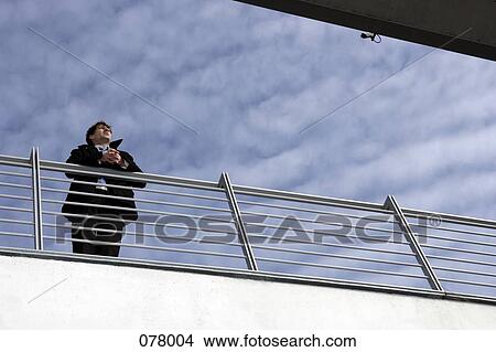 A businessman leaning on a railing View Large Photo Image Picture - A businessman leaning on a railing . Fotosearch