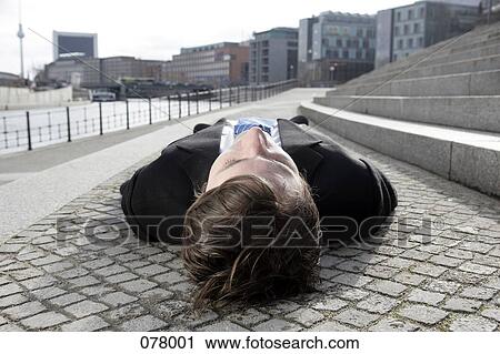 A businessman lying down near a street, Berlin, Germany View Large Photo Image Stock Image - A businessman lying down near a street, Berlin, Germany. Fotosearch