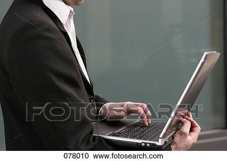 Stock Image - A businessman typing on a laptop computer. Fotosearch