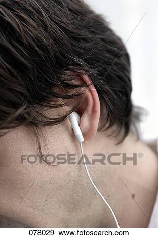 A man listening to music through earphones View Large Photo Image Stock Photo - A man listening to music through earphones. Fotosearch