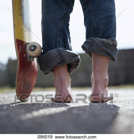 Close up of man standing with skateboard View Large Photo Image Stock Photo - Close up of man standing with skateboard. Fotosearch
