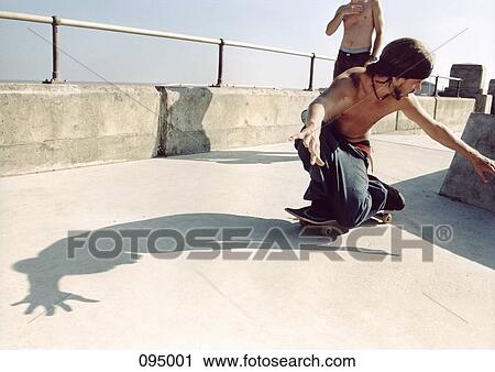 Man kneeling on skateboard View Large Photo Image Stock Image - Man kneeling on skateboard. Fotosearch