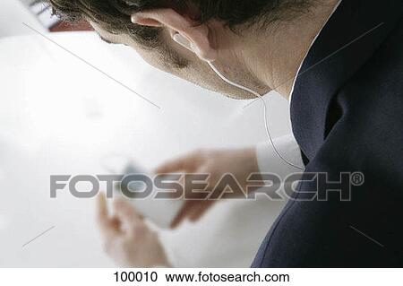 Stock Image - Man listening to MP3 player. Fotosearch