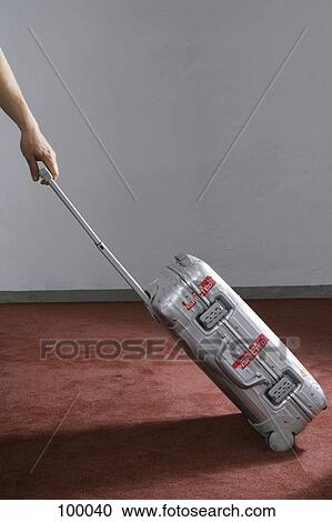 Stock Image - Man pulling rolling suitcase. Fotosearch