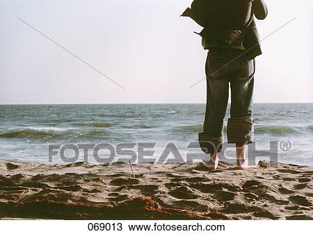 Stock Image - A man standing on a beach. Fotosearch