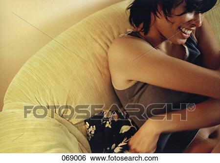 Stock Photograph - A woman sitting on a couch. Fotosearch