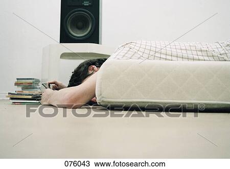 A person lying on a bed, below a speaker View Large Photo Image Stock Image - A person lying on a bed, below a speaker. Fotosearch