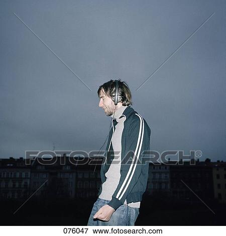 A young man listening to music on headphones View Large Photo Image Stock Photo - A young man listening to music on headphones. Fotosearch