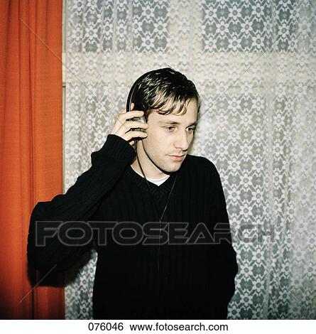 A young man listening to music on headphones View Large Photo Image Stock Photograph - A young man listening to music on headphones. Fotosearch