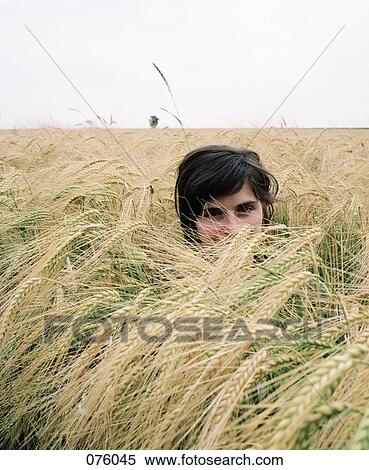 A young woman standing in a field View Large Photo Image Stock Photography - A young woman standing in a field. Fotosearch