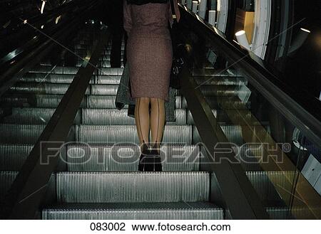 A woman ascending on an escalator View Large Photo Image Stock Image - A woman ascending on an escalator. Fotosearch