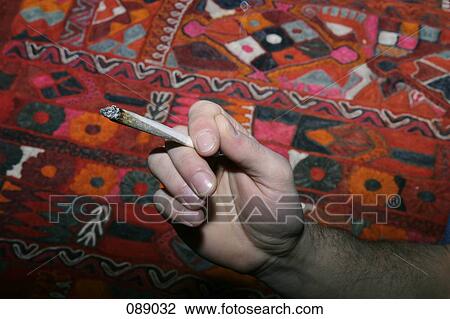 Stock Image - Man holding hand rolled cigarette. Fotosearch