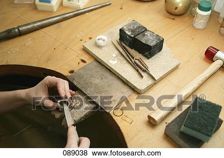 Stock Photo - Woman shaping metal with tool. Fotosearch