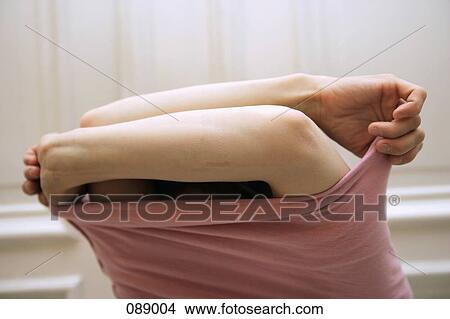 Picture - Woman taking off sweater. Fotosearch