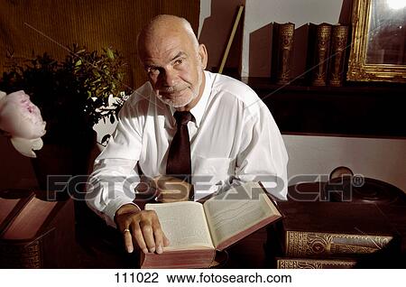 Man sitting at desk with books View Large Photo Image Stock Image - Man sitting at desk with books. Fotosearch