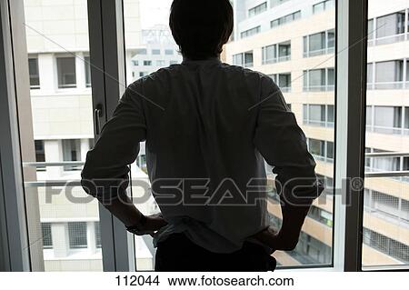 Businessman standing at window View Large Photo Image Picture - Businessman standing at window. Fotosearch