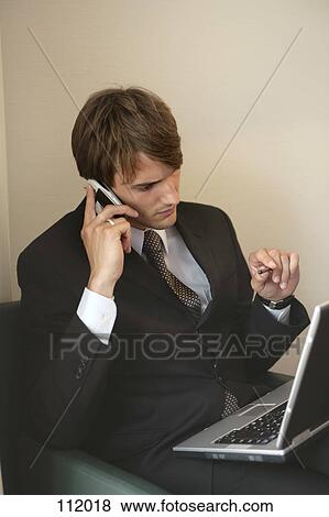 Businessman with cell phone and laptop computer View Large Photo Image Stock Photo - Businessman with cell phone and laptop computer. Fotosearch