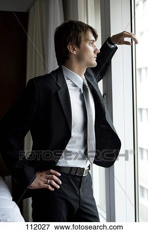 Man in suit standing at window View Large Photo Image Stock Photo - Man in suit standing at window. Fotosearch