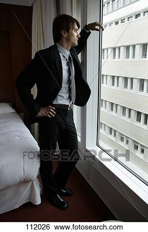 Stock Photograph - Man in suit standing at window. Fotosearch