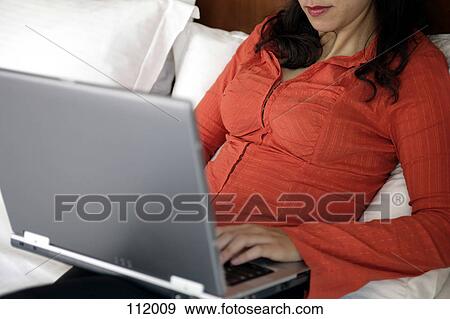 Woman using laptop computer in bed View Large Photo Image Stock Photo - Woman using laptop computer in bed. Fotosearch