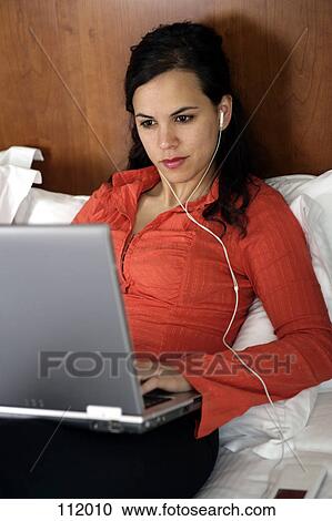 Stock Image - Woman with MP3 player and laptop computer. Fotosearch