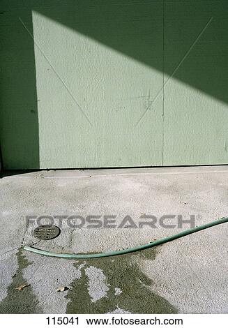 Stock Image - Garden hose on ground. Fotosearch