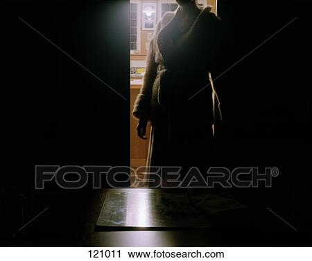 Stock Image - Woman standing in dark doorway. Fotosearch