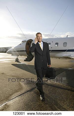 Stock Image - Businessman in front of airplane. Fotosearch