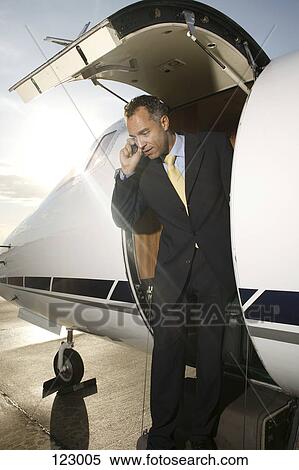 Businessman on cell phone exiting a private airplane View Large Photo Image Stock Photography - Businessman on cell phone exiting a private airplane. Fotosearch