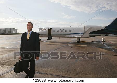 Businessman standing in front of a private airplane View Large Photo Image Stock Photo - Businessman standing in front of a private airplane. Fotosearch